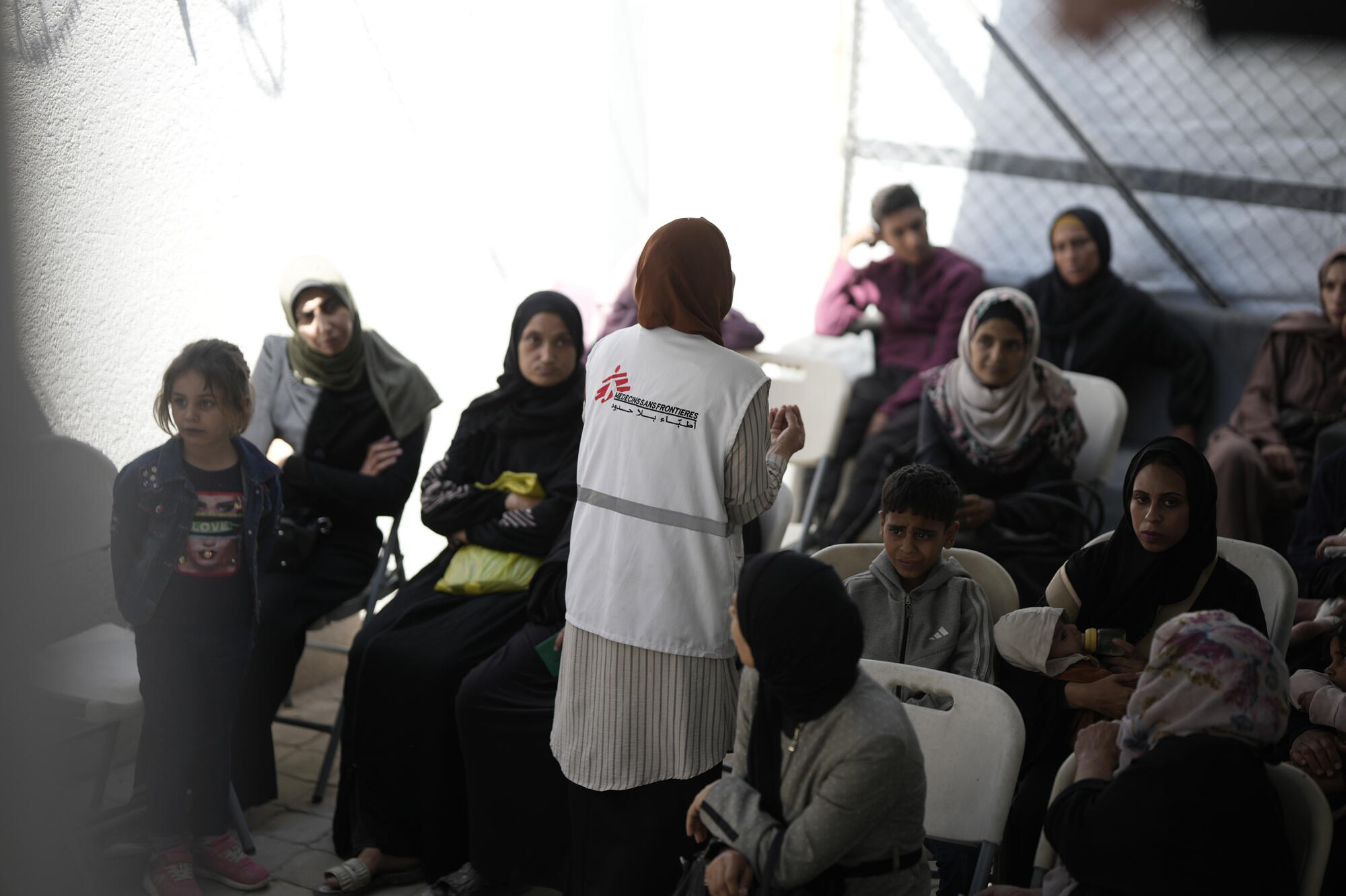 Pracownica Lekarzy bez Granic tłumaczy najważniejsze informacje dot. leczenia niedożywienia w Strefie Gazy pacjentom czekającym na badanie. Gaza, czerwiec 2025.