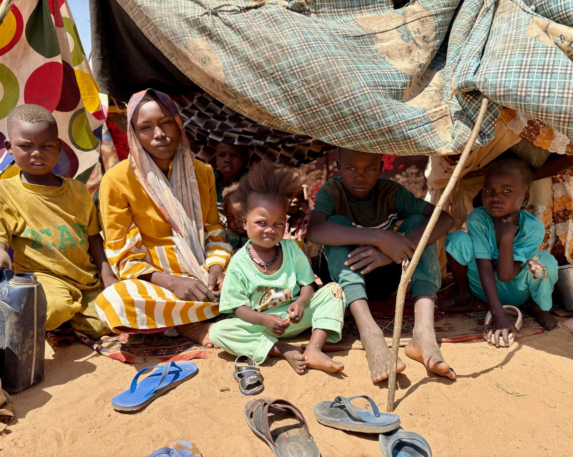Prowizoryczne schronienie zbudowane z czterech drewnianych słupów i prześcieradeł, w którym mieszka Hawa Abdallah wraz z mężem i pięciorgiem dzieci. Rodzina przybyła do Tawili 15 października po ucieczce przed intensywnymi bombardowaniami, które miały miejsce 11 października w Al-Faszir. Sudan, październik 2025.