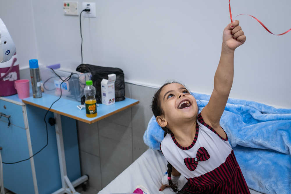 Czteroletnia Hala bawi się balonikiem na dzień po operacji rekonstrukcji stopy przeprowadzonej w szpitalu Al-Awda w Gazie. Palestyna, 2022, zdjęcie: Virginie Nguyen Hoang